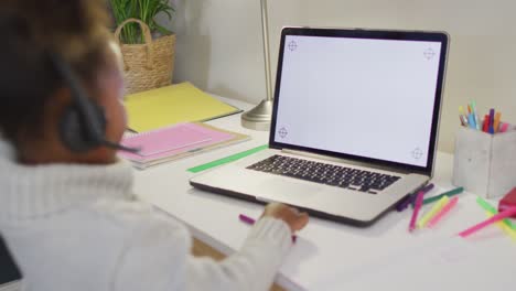 African-american-girl-sitting-at-table-and-having-video-call