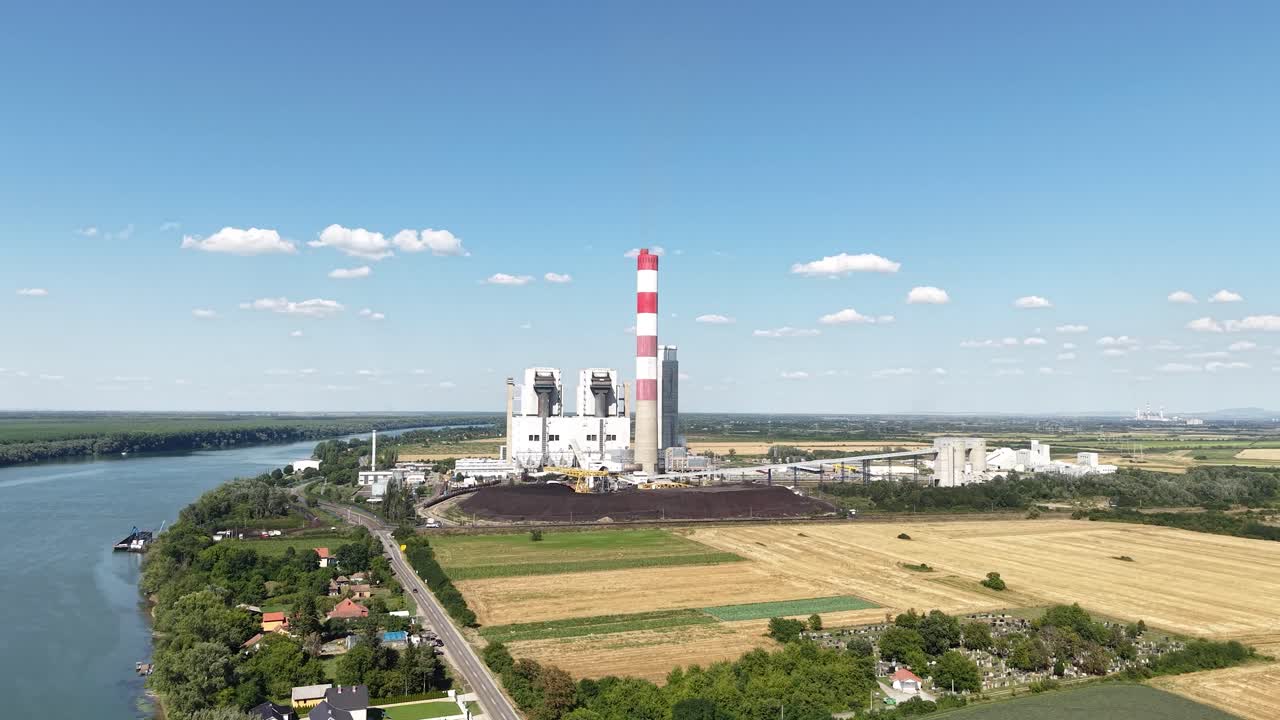 Ripresa aerea di una centrale elettrica industriale a carbone in un paesaggio aperto vicino al fiume, infrastruttura energetica
