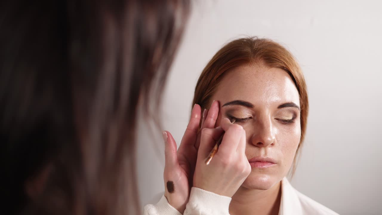 artista de maquillaje aplicando sombra de ojos