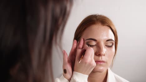 artista de maquillaje aplicando sombra de ojos