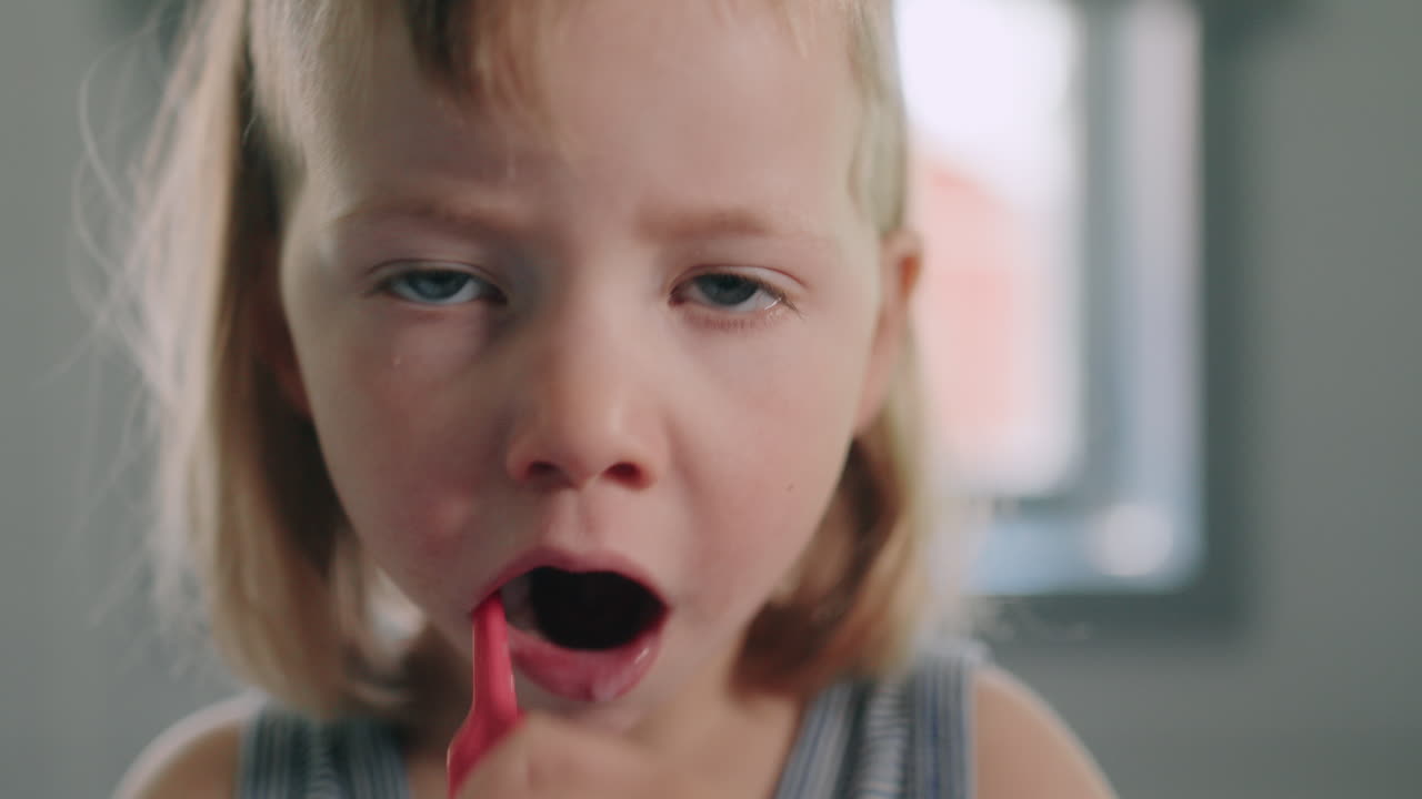 Primo piano frontale di un bambino che si lava i denti con energia dopo colazione, routine mattutina.
