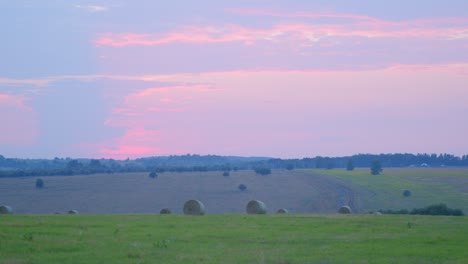 field after harvest with straw bales at sunset.