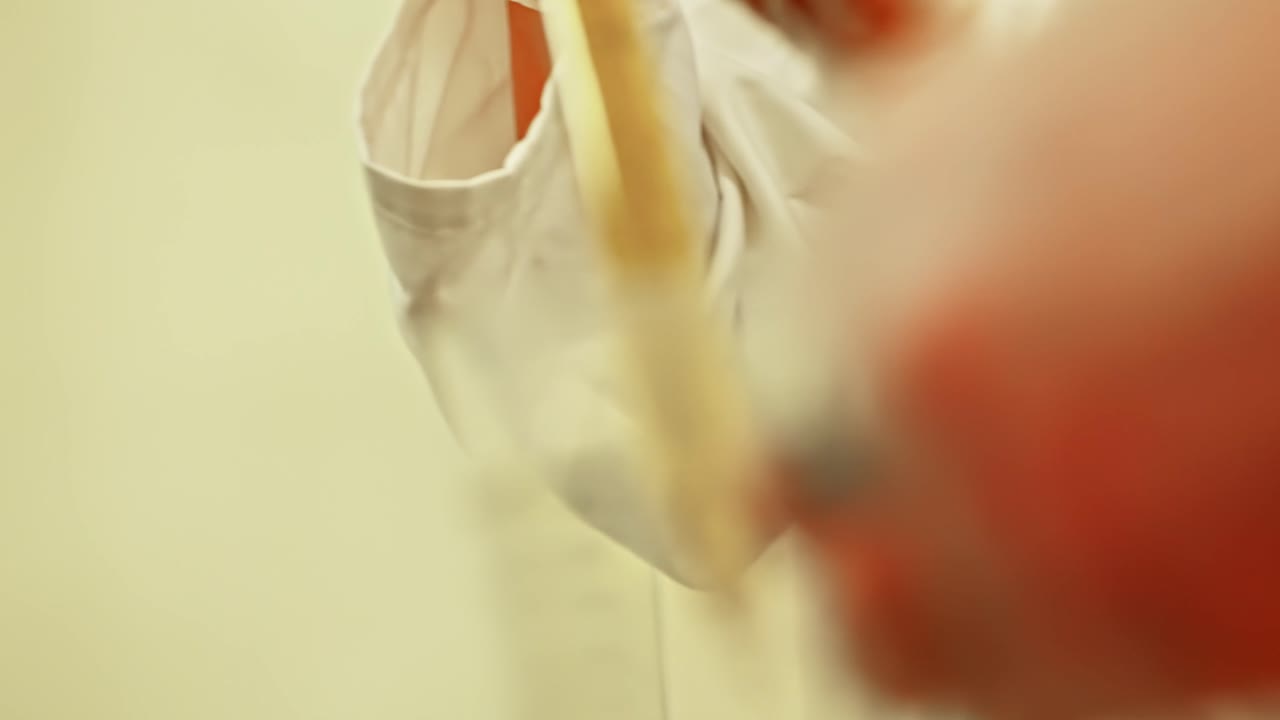 Close up of a female chemist pouring liquid chemical into laboratory glassware during a science experiment
