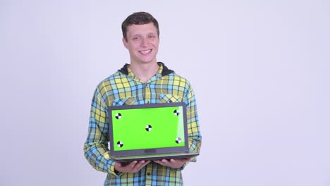 joven feliz, guapo y hipster con una computadora portátil