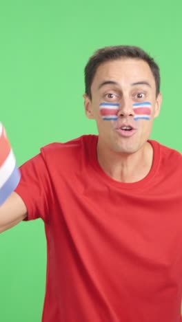 man cheering for costa rica screaming and waving a national flag