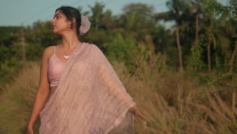 mujer con un sari tradicional caminando por un campo al atardecer, estado de ánimo reflexivo