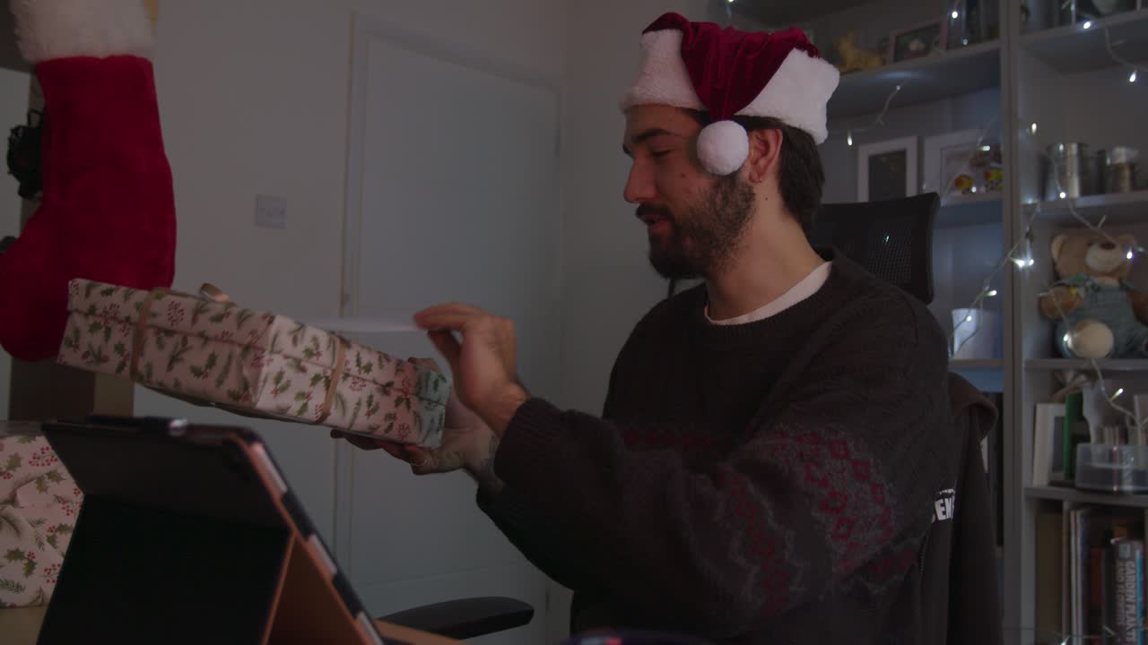 hombre mostrando un regalo de navidad en una videollamada mientras usa un sombrero de navidad