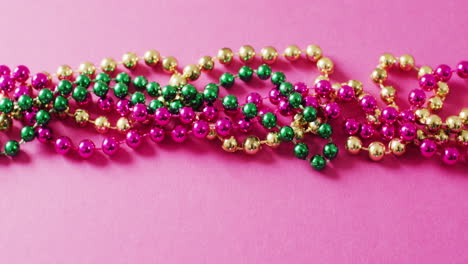 video of pink, gold and green mardi gras carnival beads on pink background