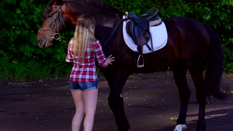 young blonde woman in a plaid shirt takes a walk with his horse. summer sunny evening.