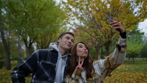 Graciosa-Pareja-Joven-Enamorada-Tomándose-Selfie-En-Su-Teléfono-Móvil-En-El-Parque-De-Otoño.