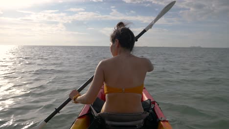 woman  kayaking and observing  the sea,against the sun