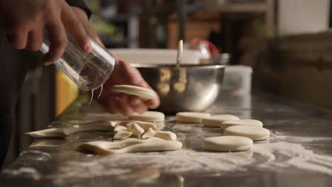 chef using glass to cut out dough circles on countertop, preparing cookies