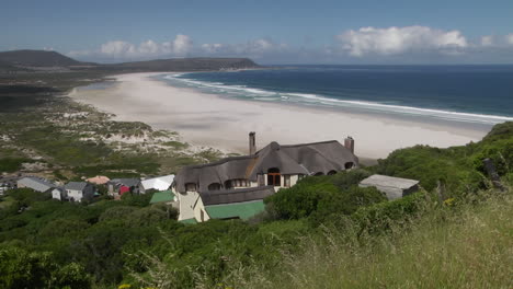 waves slowly breaking on south african beach shoreline viewed from grassland. locked off, wide angle