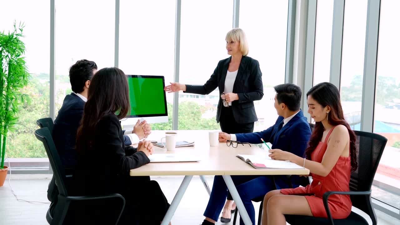 녹색 스크린을 가진 회의실에 있는 비즈니스 사람들