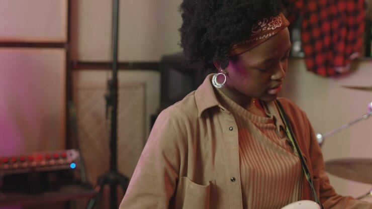Female Guitar Player And Singer Rehearsing In Recording Studio
