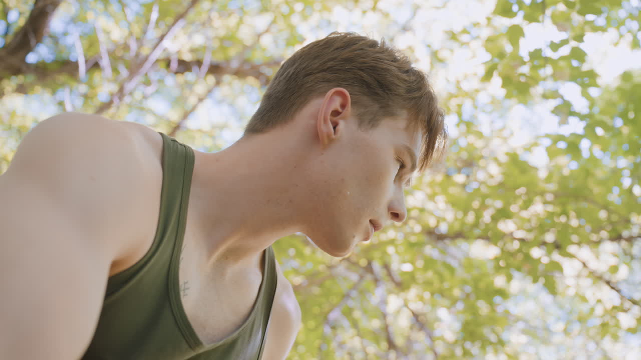 Soldier stands up and looks in different directions while putting on jacket, trying to listen attentively for any strange movements in the surrounding forest environment, preparing for action