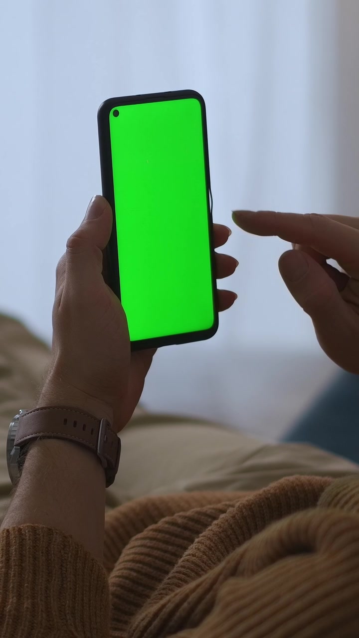 Primo piano di mani che scorrono e toccano uno smartphone con schermo verde