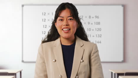 close up shot of female teacher in classroom standing in front of board teaching elementary maths lesson