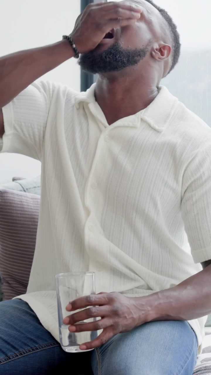 Vertical video: Spotting swing-top bottle, man in white shirt pouring into glass at home to drink