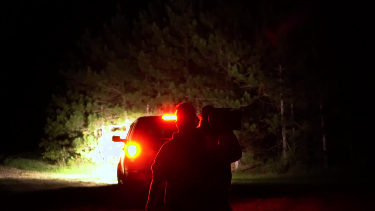 A film crew carries production equipment to a remote shoot at night