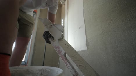 a detailed perspective of a professional applying fresh plaster to a wall with a trowel, focusing on technique and texture in an interior setting