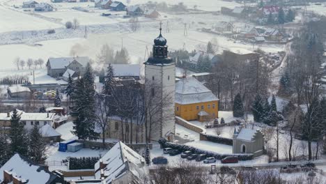 aerial establishing of historic church in lomnica, poland, surrounded by snow covered landscapes in winter, church of the immaculate conception