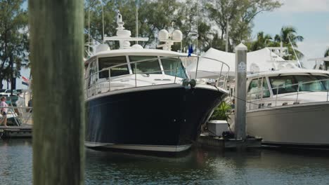 small-yacht-in-the-water,-people-walking-in-the-distance,-handheld-camera-shot