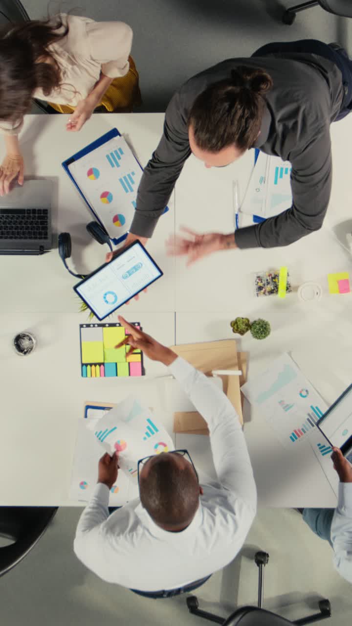 Vertical Video Top down view zoom out of business people reviewing data and proposals