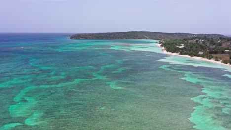 Aerial-flyover-tropical-coastline-with-clear-water-and-coral-reefs-along-coastline-of-Dominican-Republic