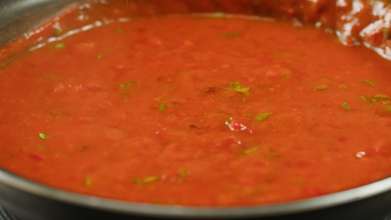 Chicken in tomato sauce is boiling on a frying pan with spices. Cooking tomato sauce curry with chicken fillet. Traditional Italian Mexican Asian dish. High quality studio shot for cafe, restaurant close up.