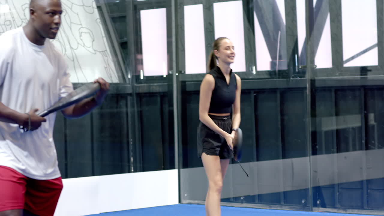 Man playing padel tennis, holding racket, focused on game on indoor court