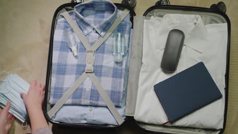 a woman packs clothes and face mask for a business trip 2