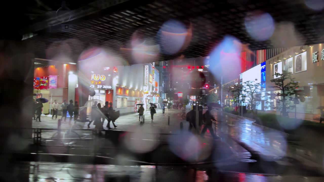 Night view of a rainy street in Tokyo with blurred lights and a construction site in the background