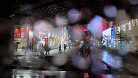 night view of a rainy street in tokyo with blurred lights and a construction site in the background