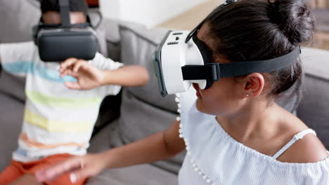 Happy-african-american-brother-and-sister-using-vr-headsets-on-sofa,-slow-motion