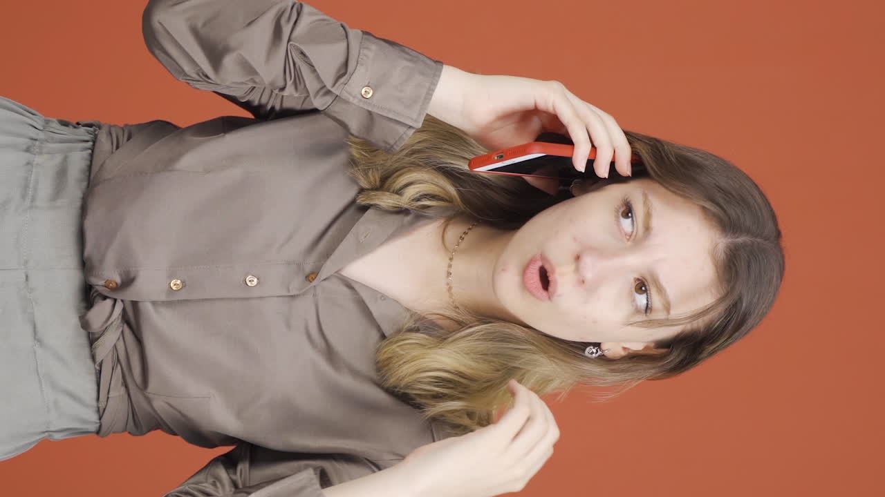 전화로 이야기하는 젊은 여성의 전화의 수직 비디오가 충전되지 않습니다.