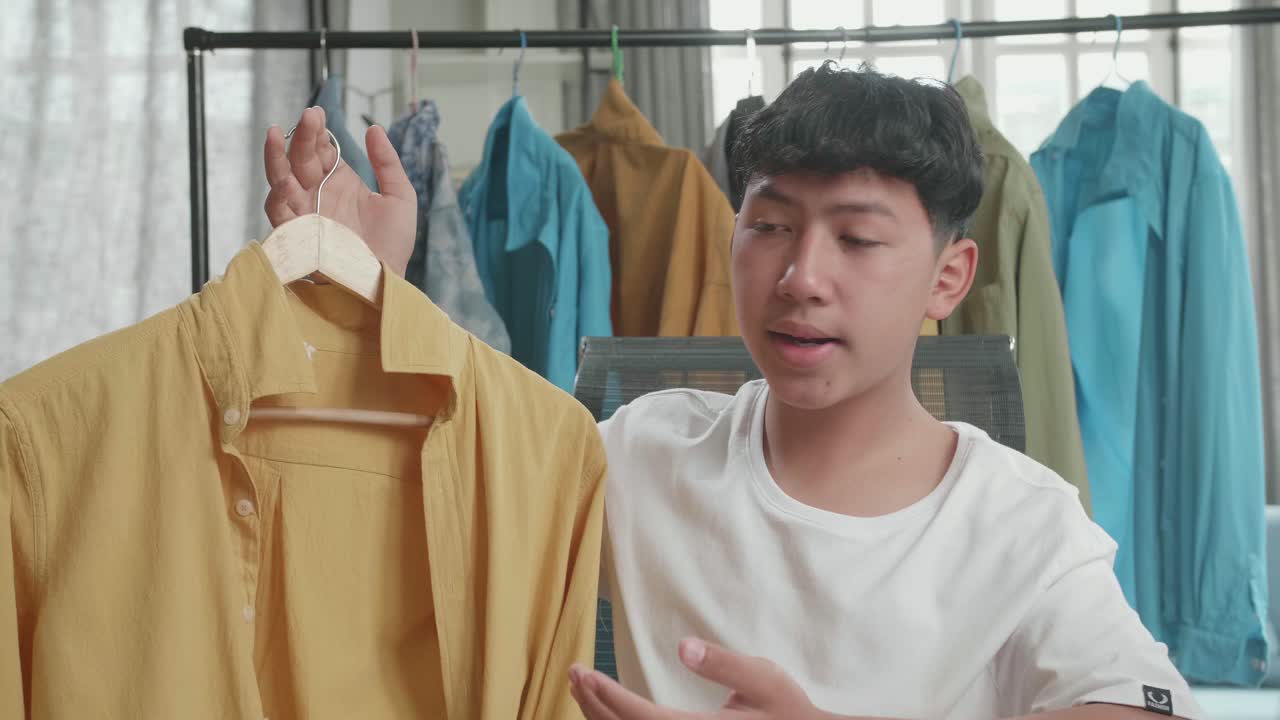 Close Up Of Asian Man Online Seller Recommending A Shirt While Using Computer For Selling Clothes At Home