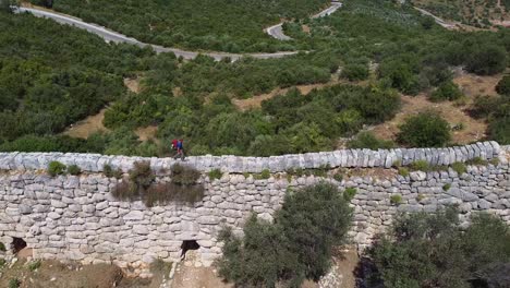 steady drone shot of a hiker waling on top of a wall along the lycian way, a marked long-distance hiking trail in southwestern turkey