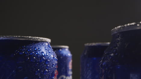 close up or macro shot of condensation droplets on takeaway cans of cold beer or soft drinks against black background