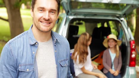 father and son smiling at camera in front of car