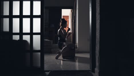 Young-woman-in-dark-room-dressing-up-in-front-of-the-mirror