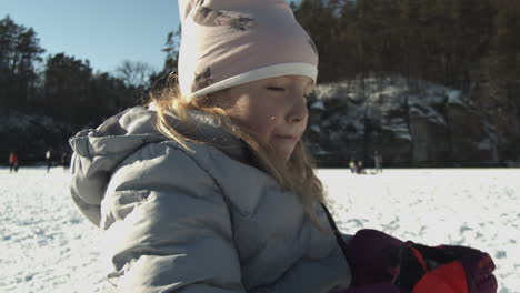 young girl quenching her thirst after playing in the snow in lhotka frozen lake in kokorin, czech republic - close up slow-motion static shot