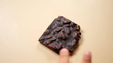 close up of a hand holding a dark chocolate bar with pistachios