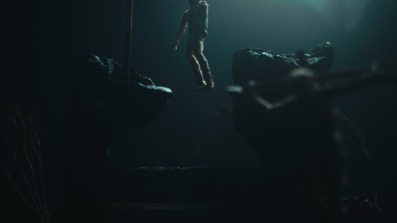 A miniature mummified doll hanging on the gallows at night