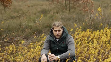 hombre fumando un sigaret mientras se sienta y descansa en el bosque de otoño