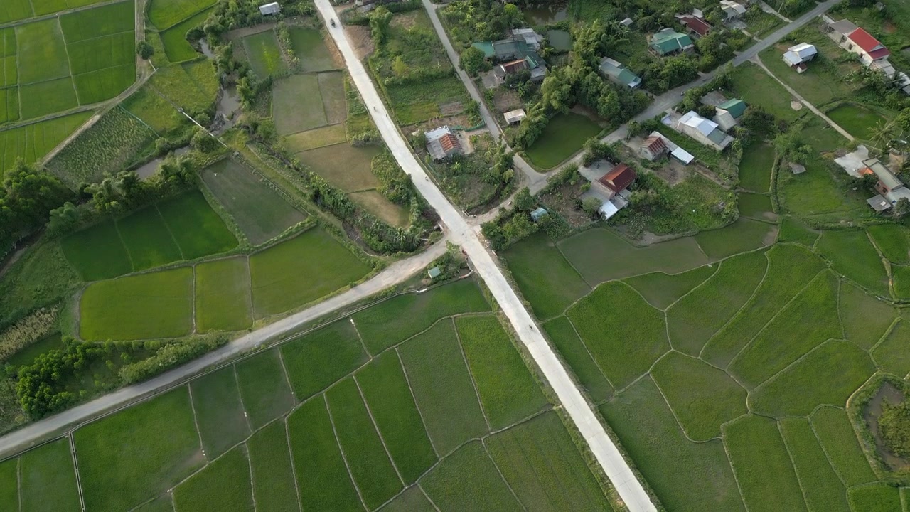 สกู๊ตเตอร์ขับผ่านทุ่งนาและสี่แยกชนบทในเวียดนามกลาง โดรนบินลง 4K 30FPS