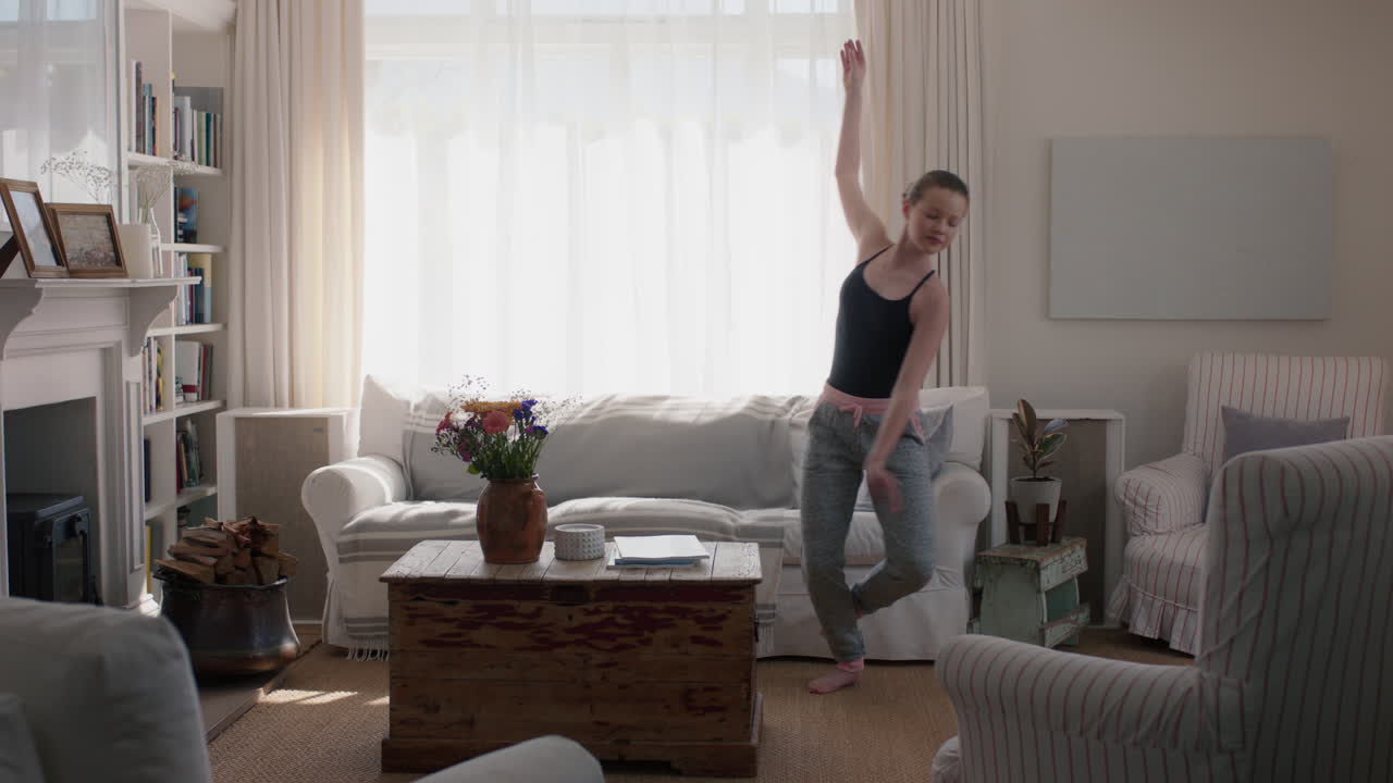 아름다운 십대 소녀가 집에서 춤을 추고 발레 댄스 동작을 연습하고 거실에서 재미있게 연습하고 있습니다.