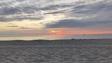 Zeitraffer-Sonnenuntergang-An-Der-Ostsee-Mit-Vorbeifahrendem-Schiff-Im-Hintergrund-Und-Sand-Im-Vordergrund