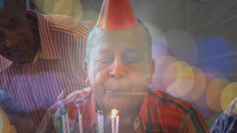 Animation-of-glowing-light-over-portrait-of-happy-senior-man-wearing-party-hat-blowing-candles