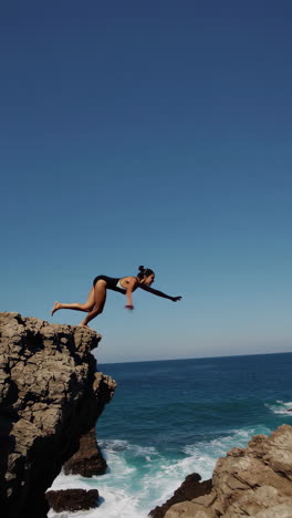woman preparing to dive from a cliff into the clear blue ocean